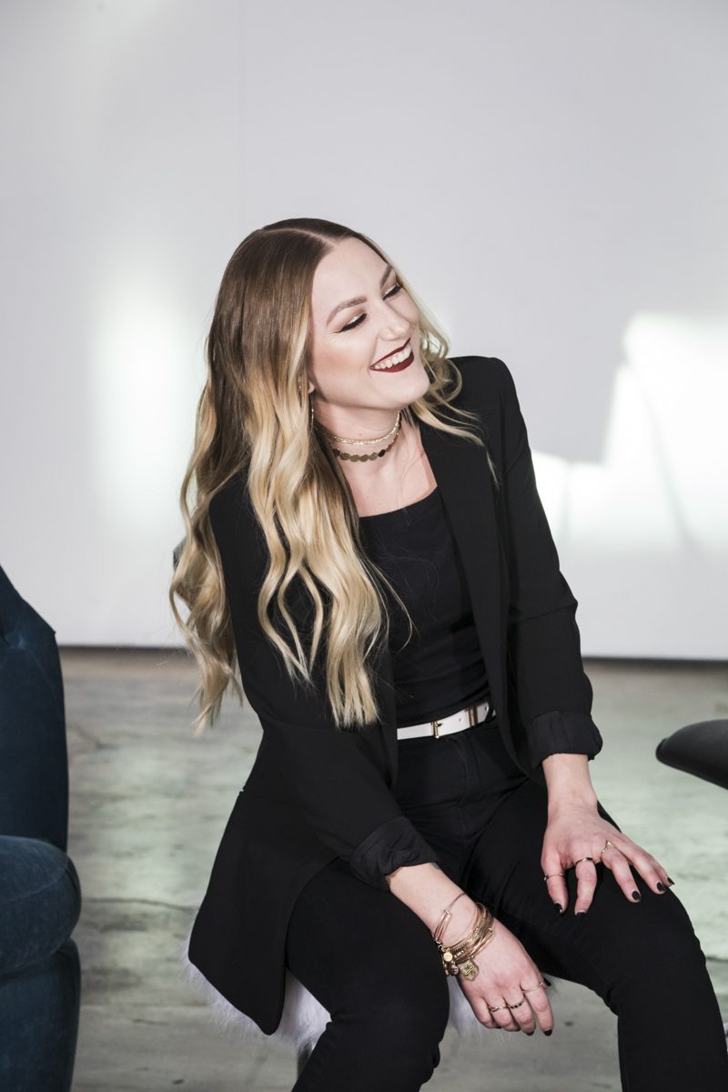 Woman smiling leaning to one side with hand on knee.